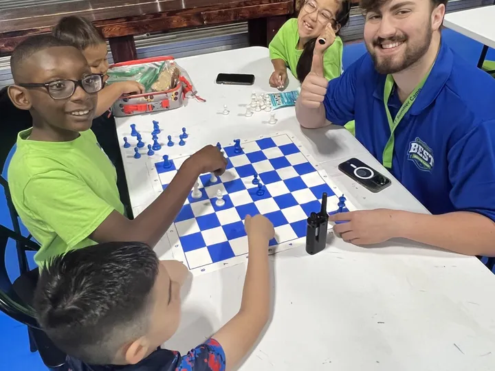 A coach playing chess with a camper