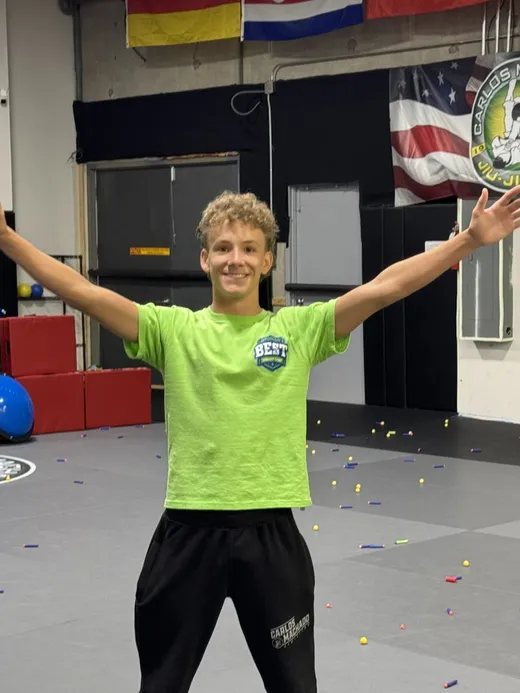 A camper celebrating on the martial arts mats