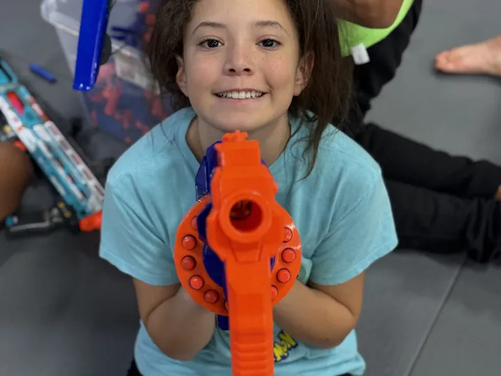 A camper aiming a foam blaster during an active game