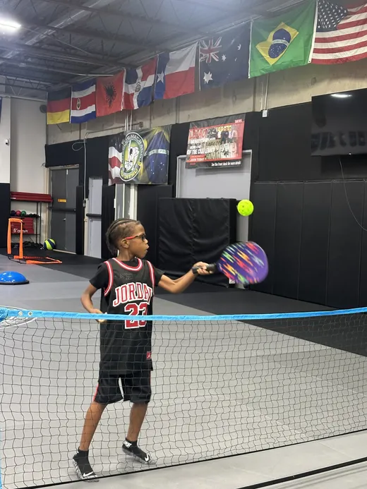 A camper serving over a net during a racket game